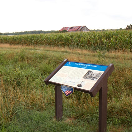 Historical sign in a field with a barn in the background